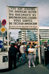 Shelby standing under reproduction sign at Checkpoint Charlie.